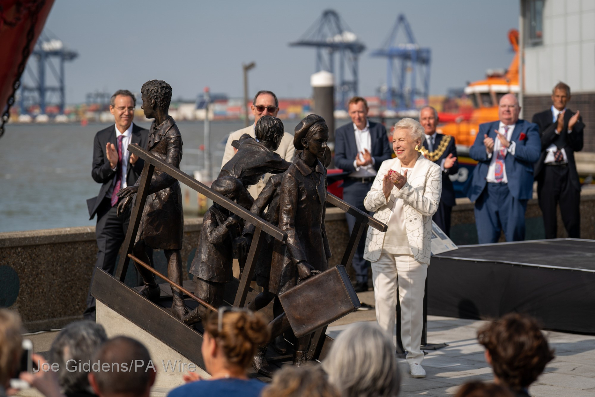 Sculpture of Kindertransport surrounded by applauding people on Harwich docks