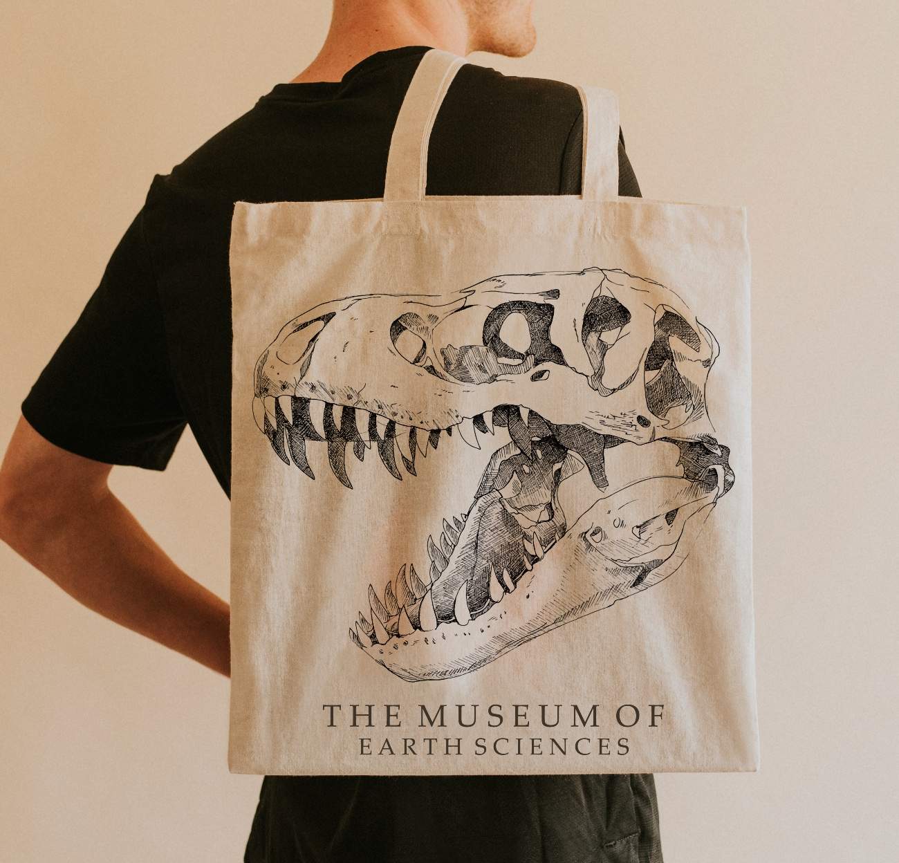 Photo of man carrying Museum of Earth Sciences totebag illustrated with T-Rex skull