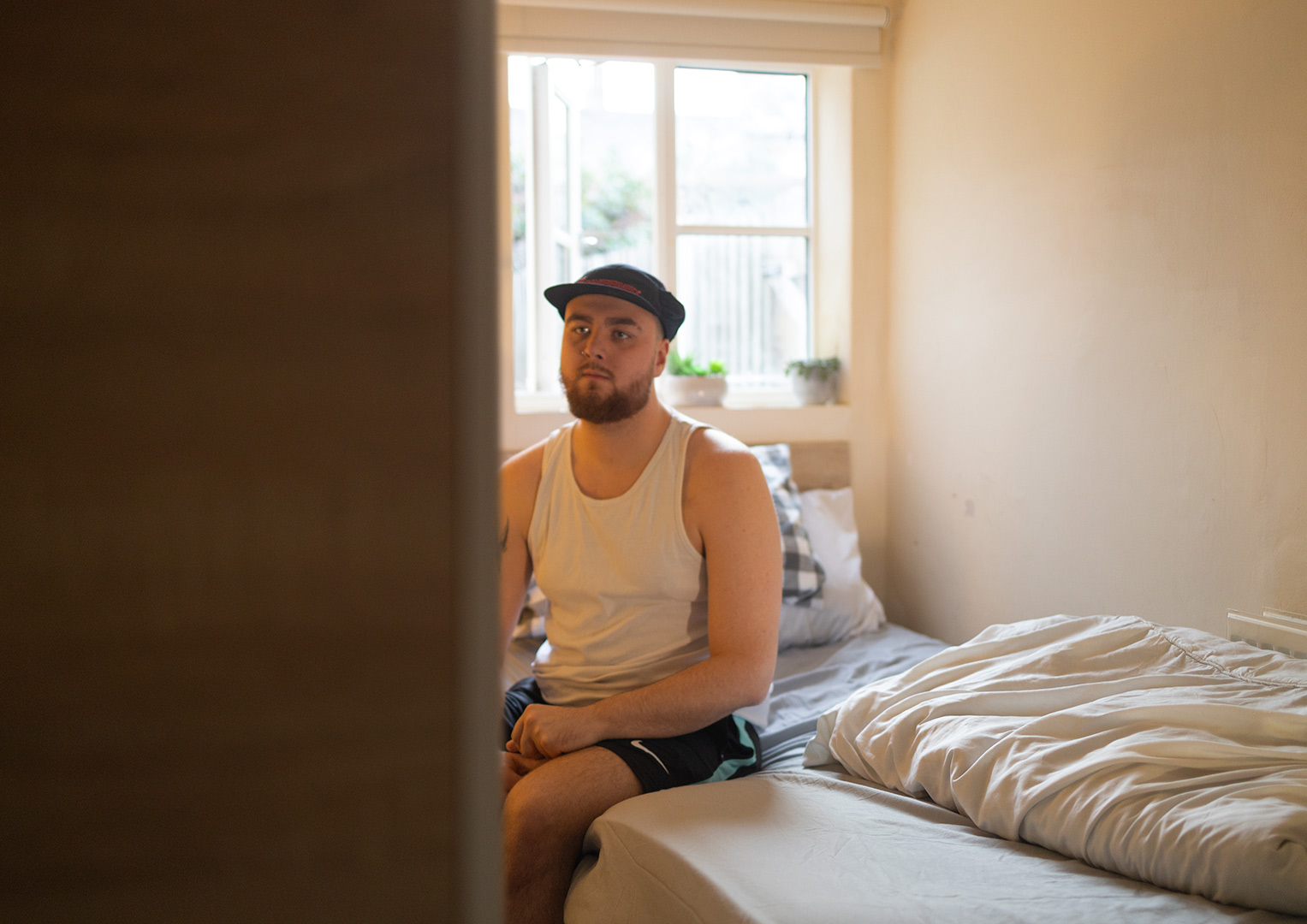 Photo of young man sitting on bed