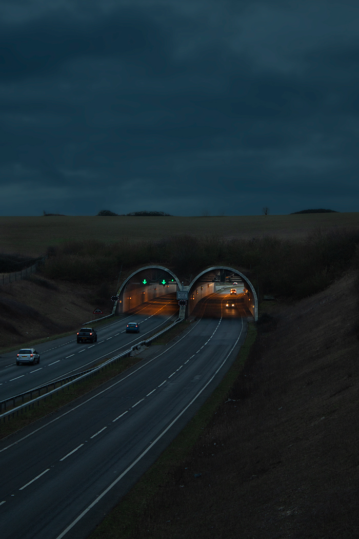 Photo of cars entering and emerging from two tunnels on road