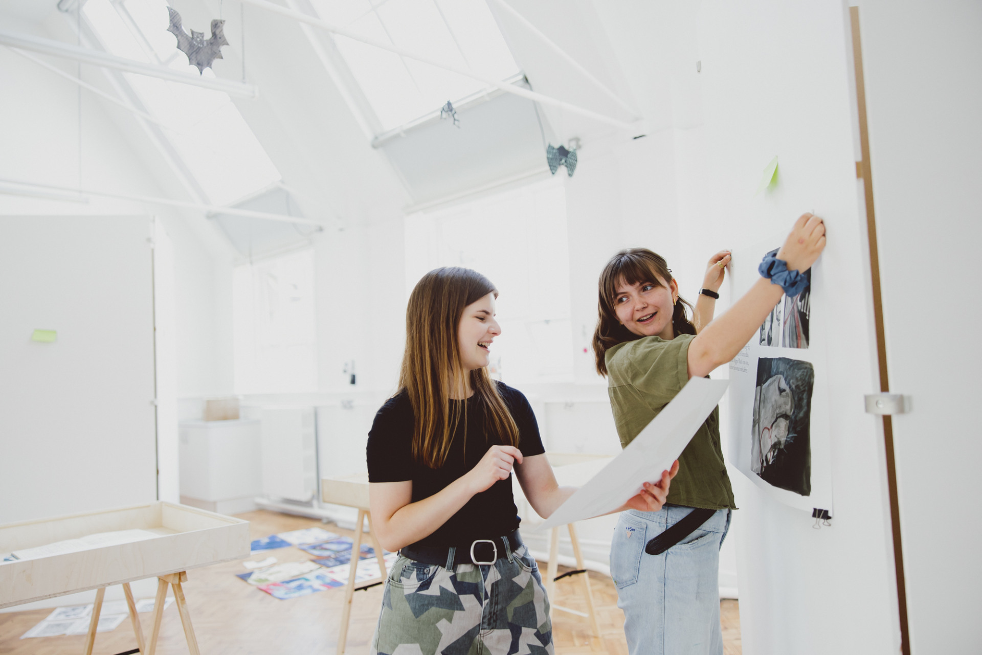 Two female students hanging work in illustration studio