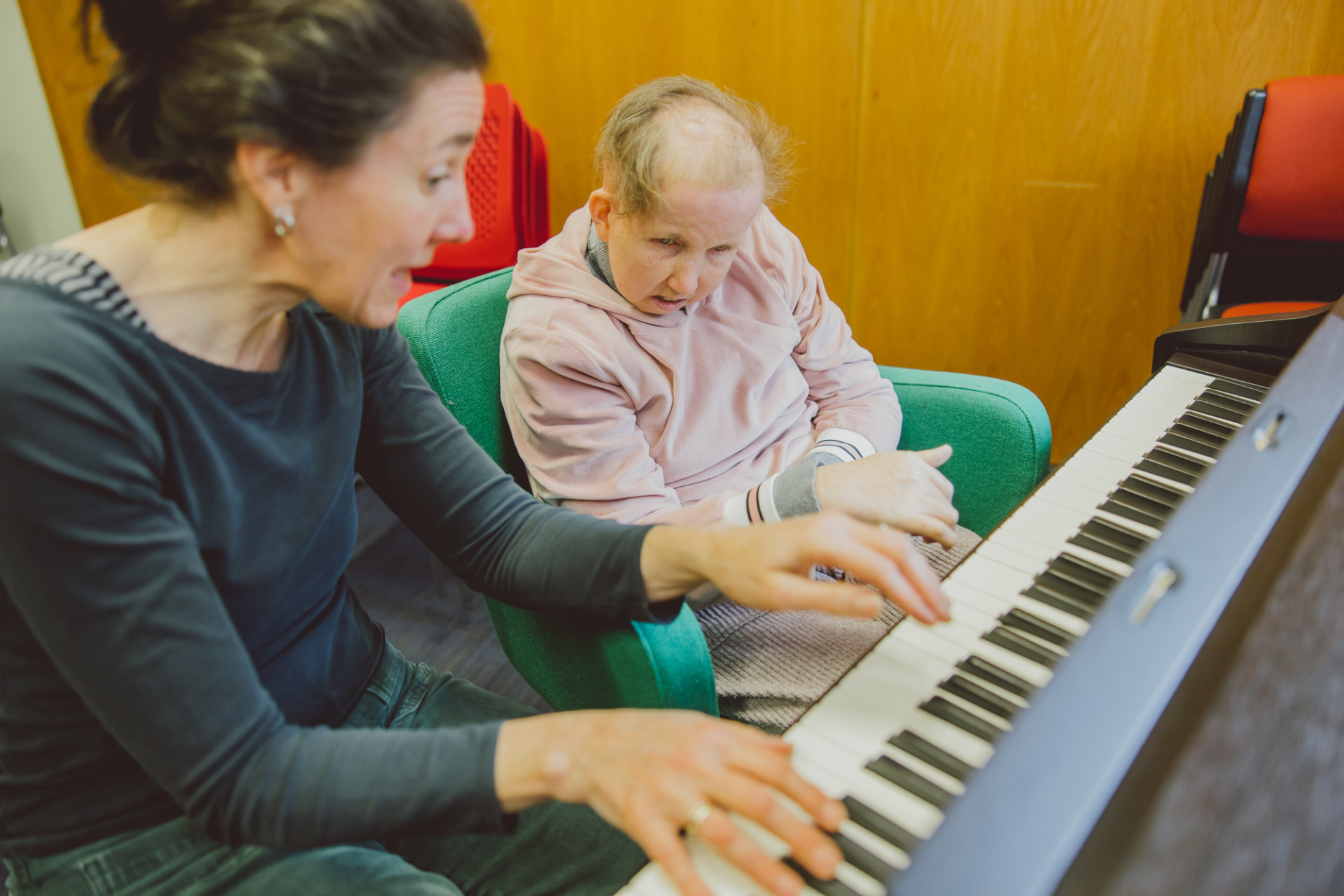 Female music therapist playing upright piano with client