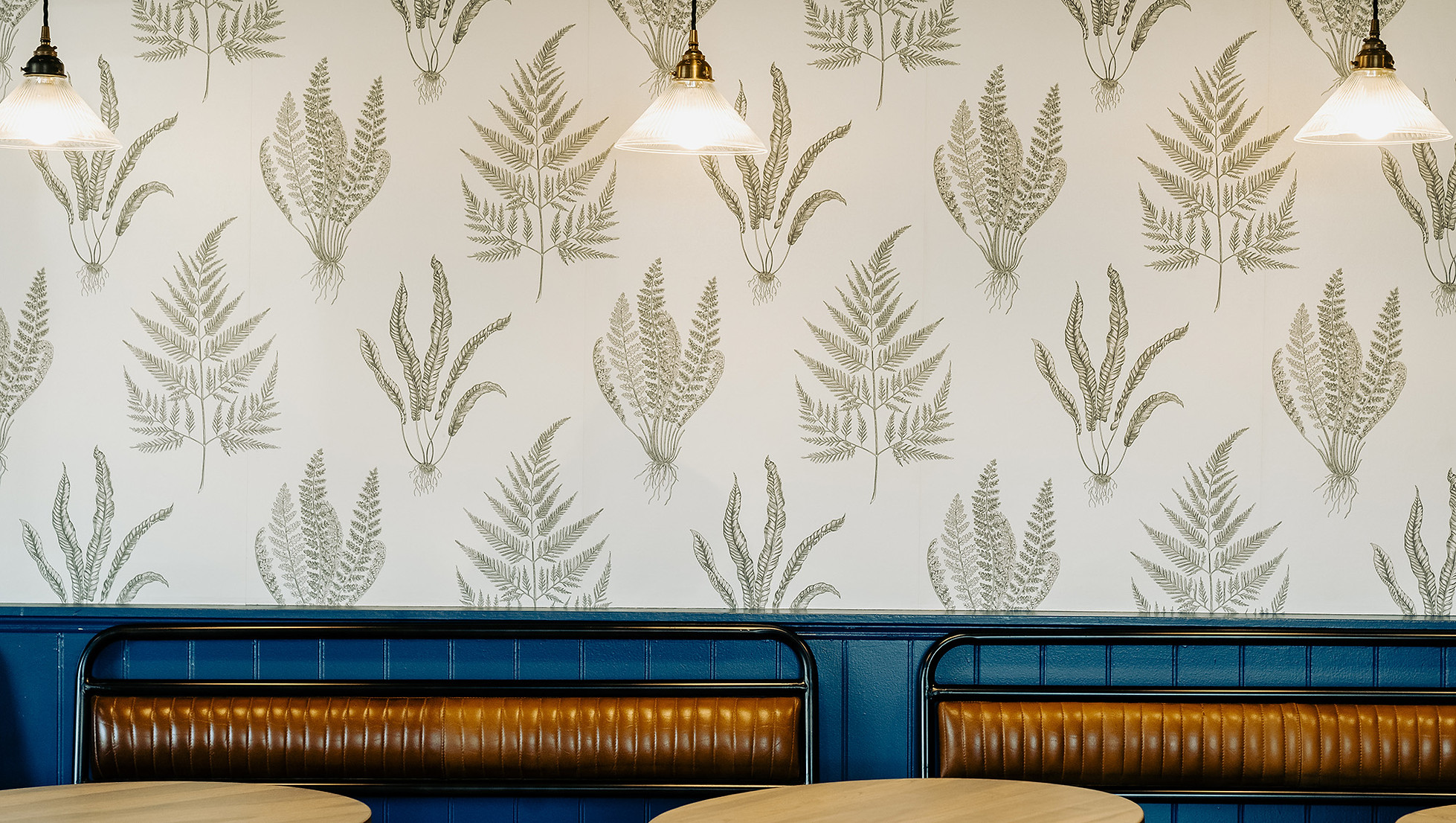 Pub interior with frond wallpaper and brown benches