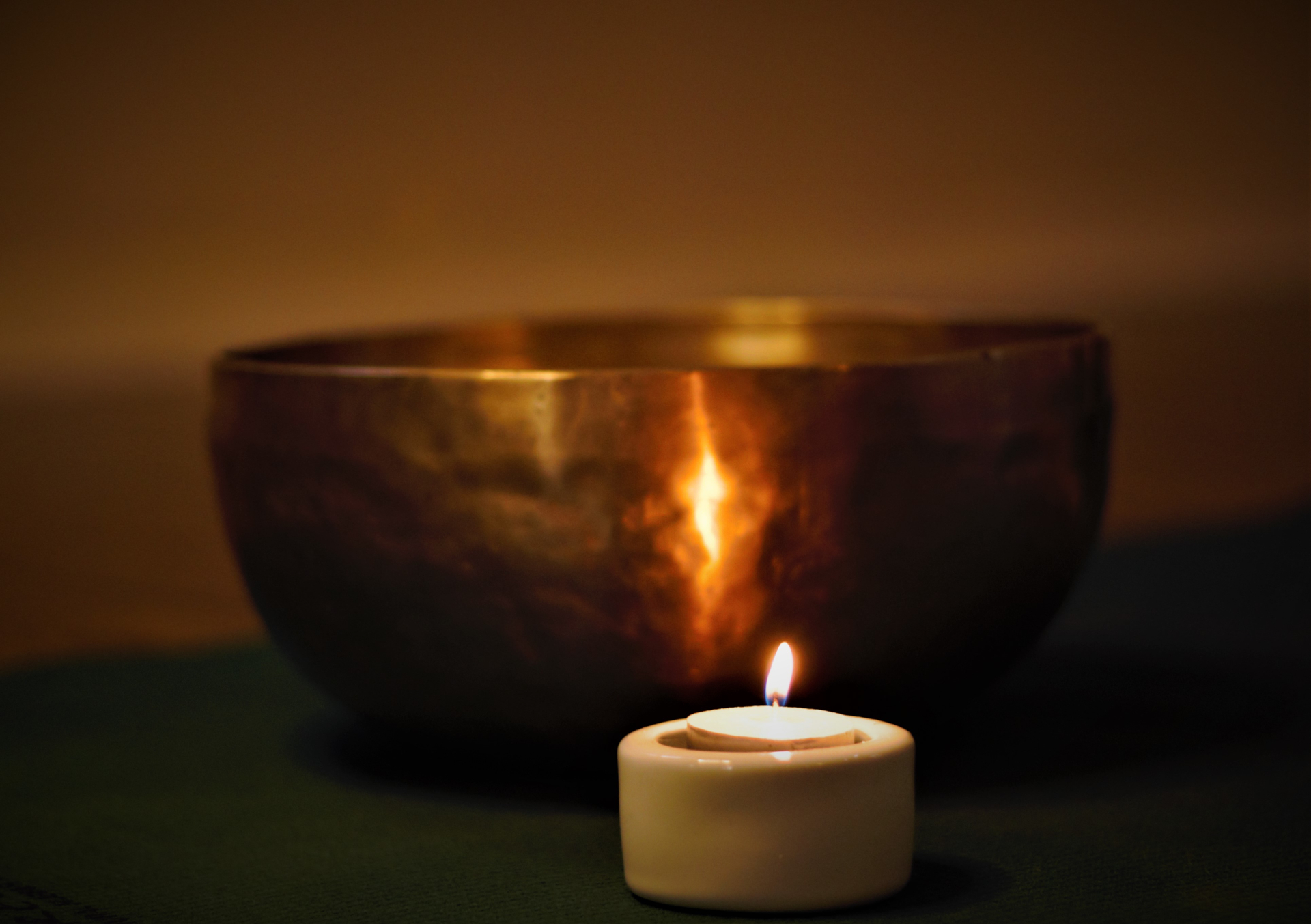 Lit tealight candle in front of bowl