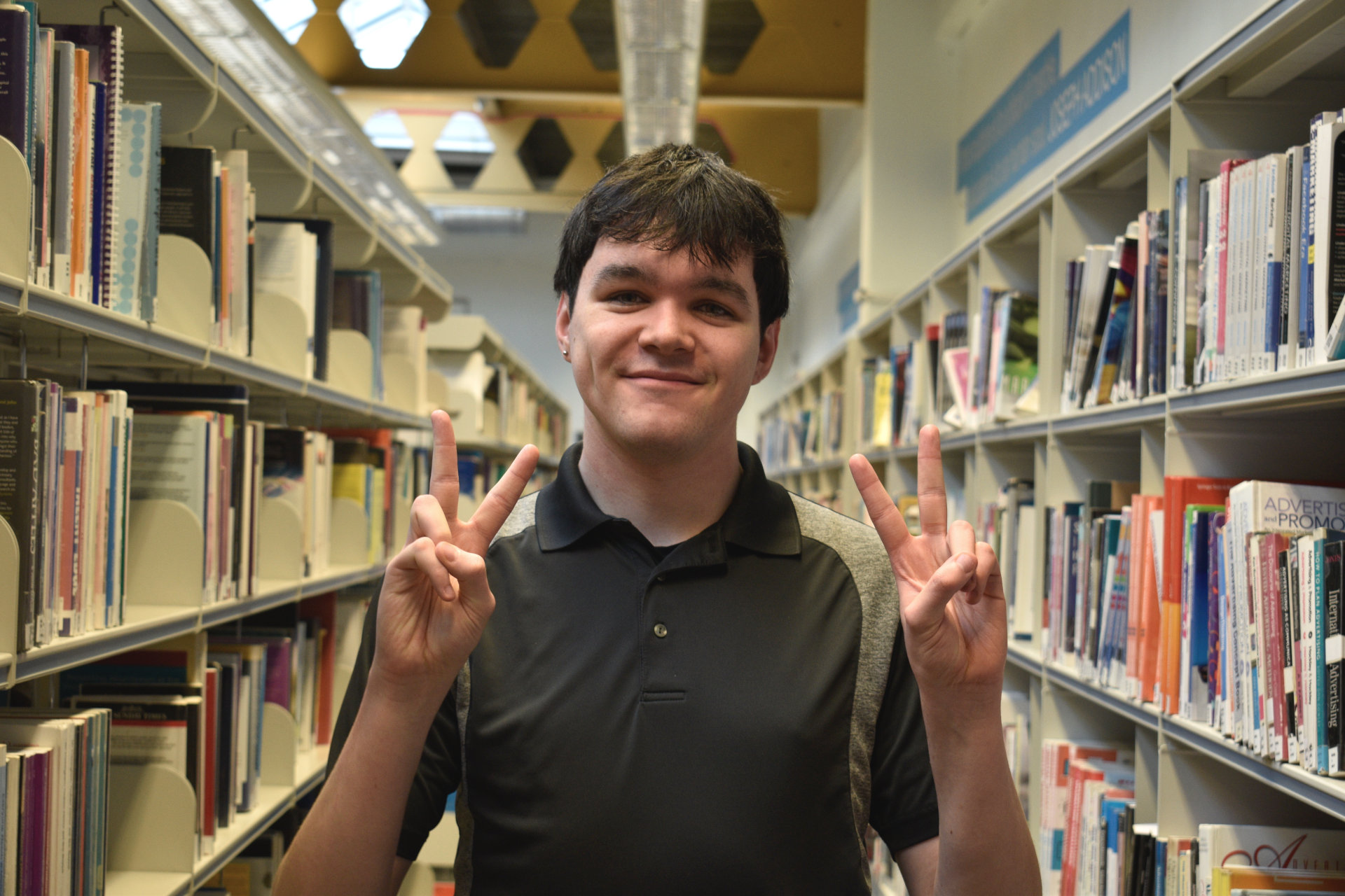 Luke Ford-Busson giving peace sign with both hands in ARU Cambridge library