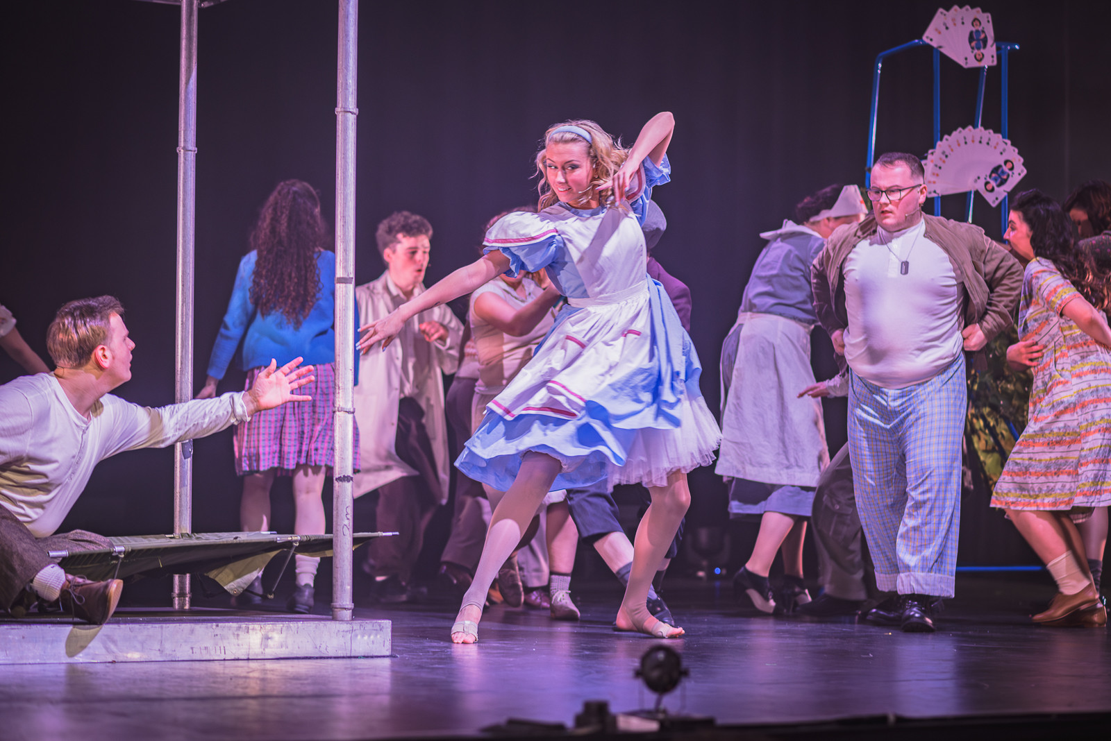 A female student in traditional Alice outfit dancing on stage