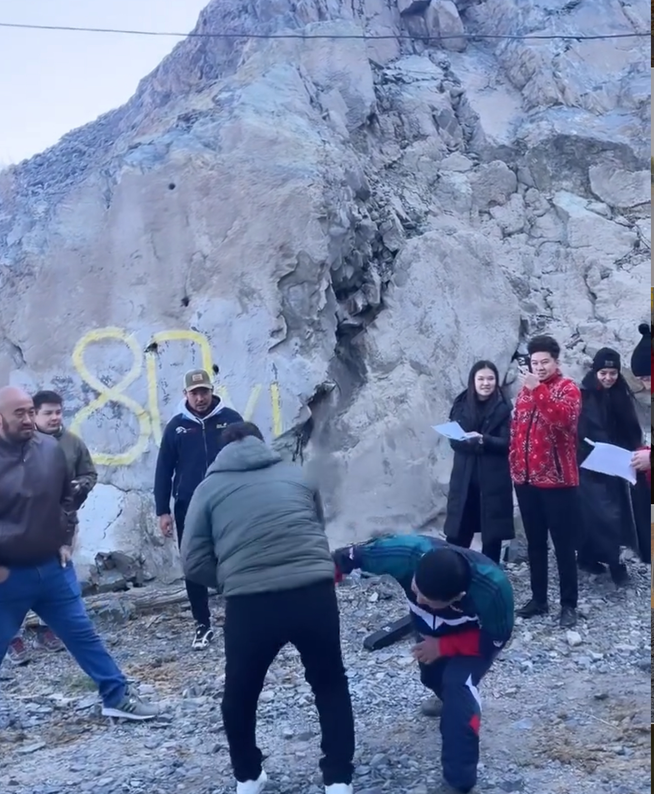 Film cast and crew in front of grey rockface