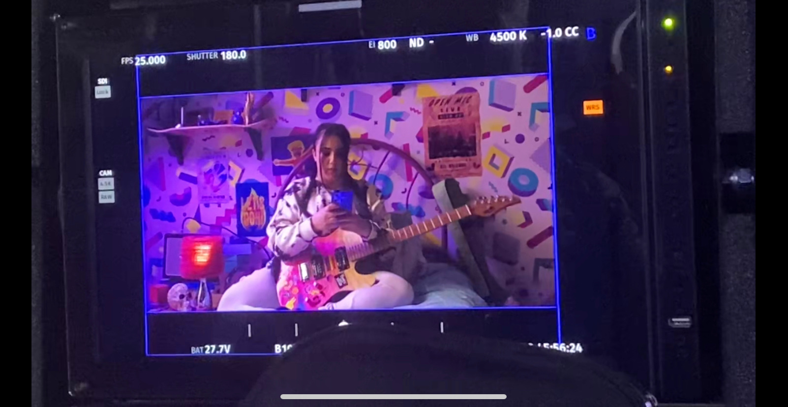 Camera view of Leila Khan on Heartstopper set, sitting on bed with guitar
