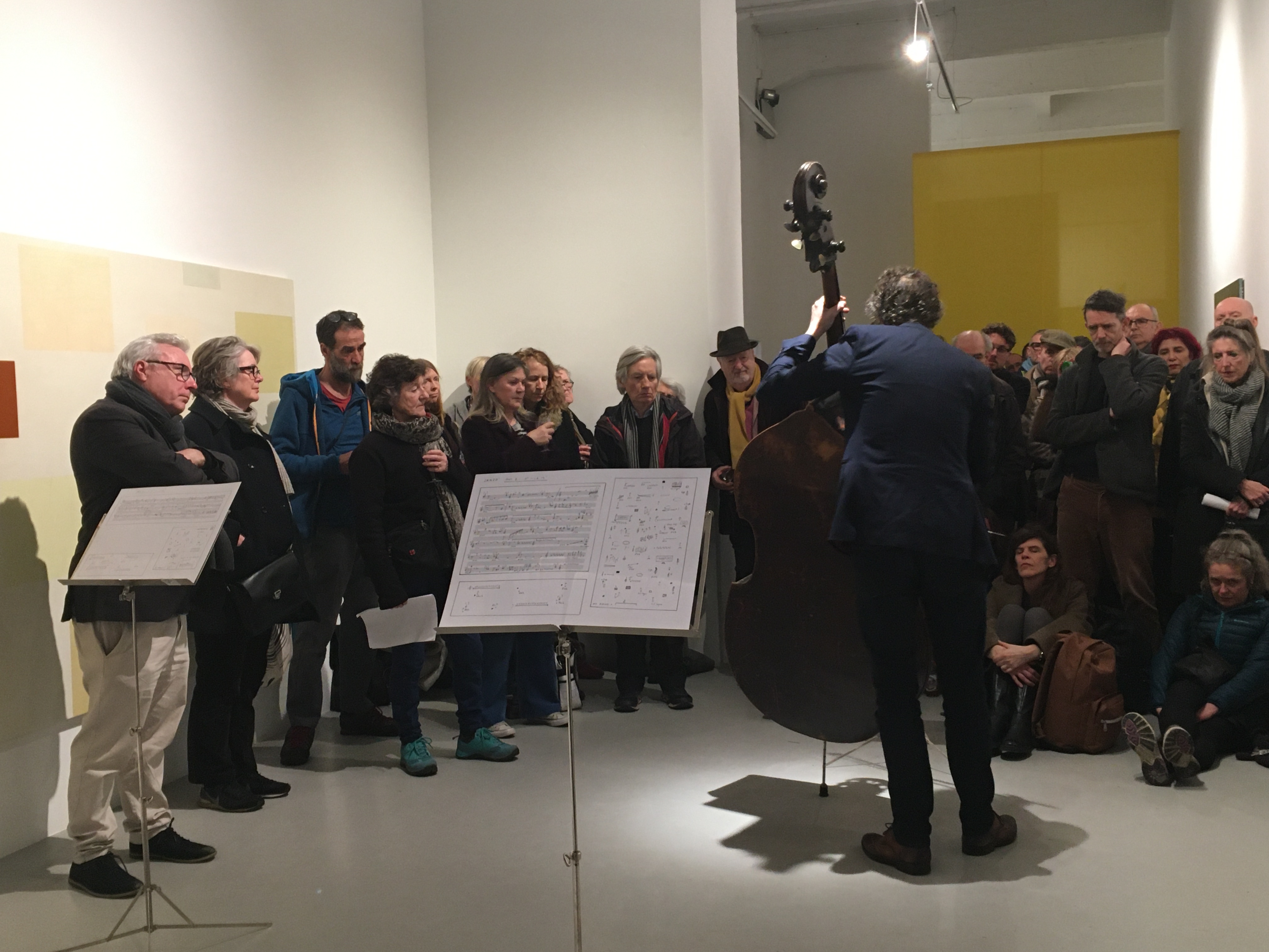 A crowd in a room around someone playing double bass