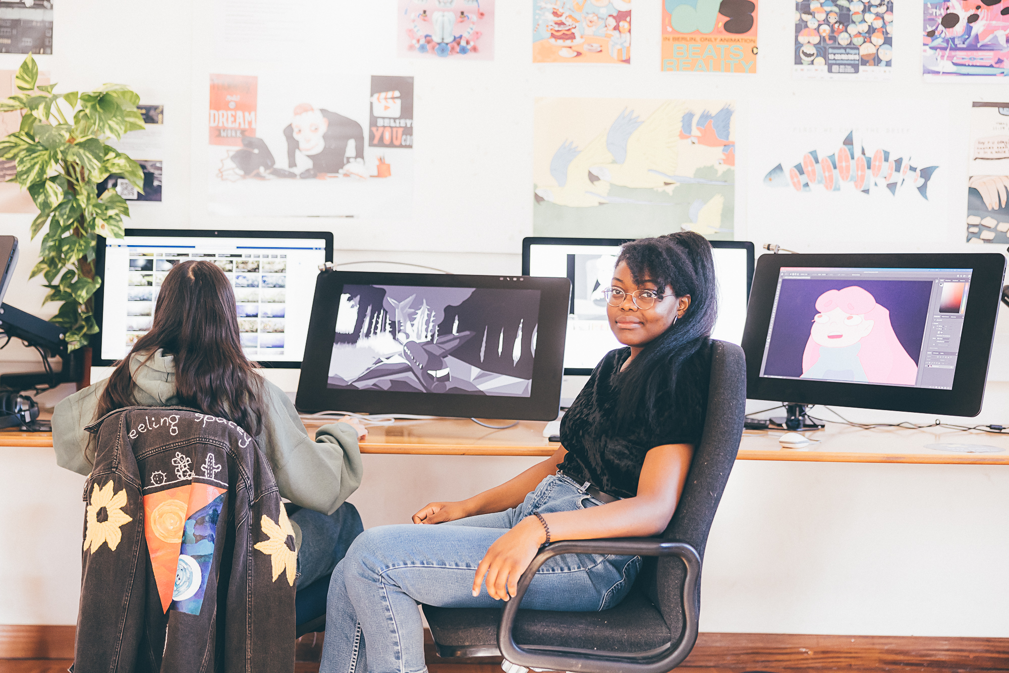 Two students sitting in front of monitors showing animation software