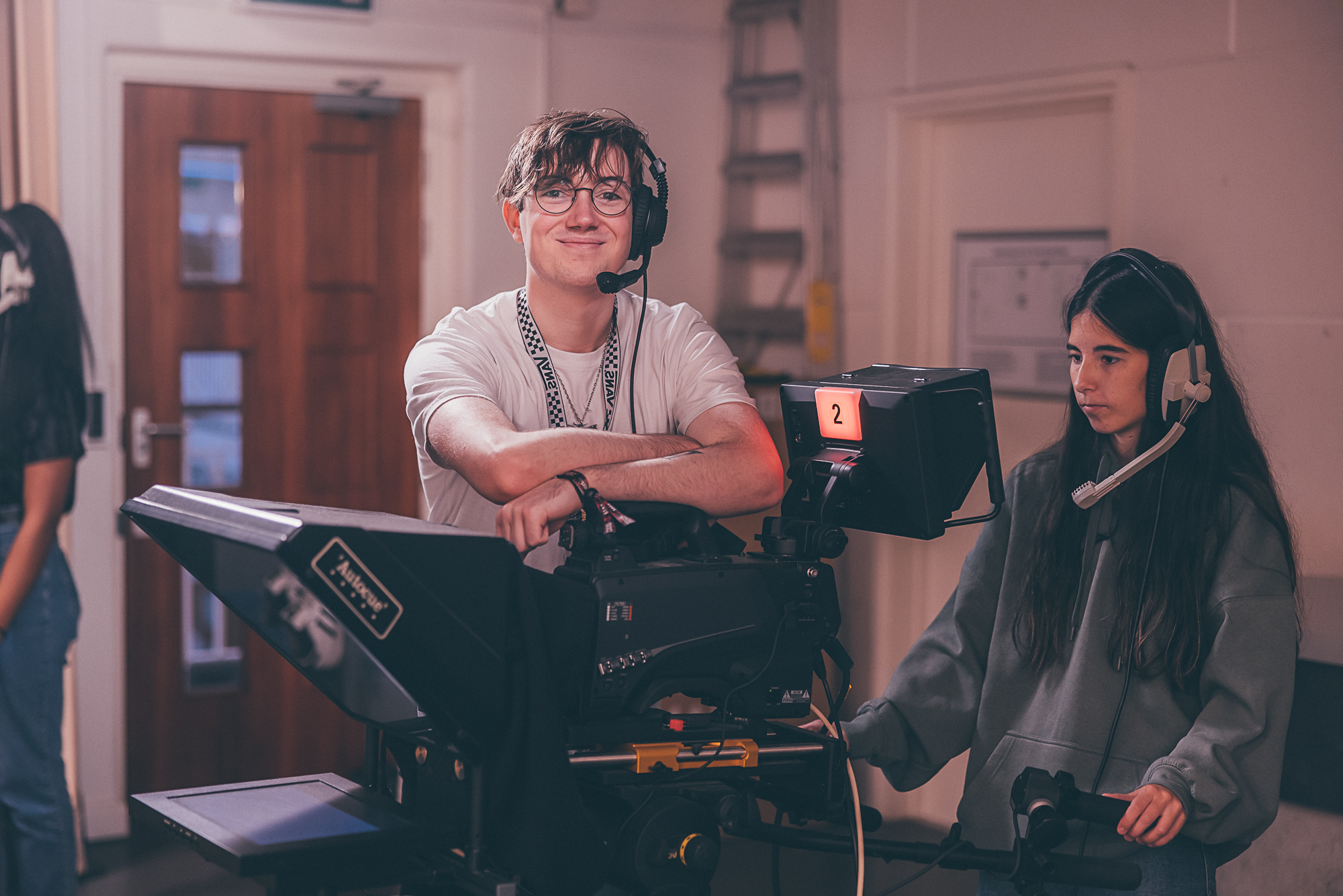 Male student leaning over film camera while female student operates it