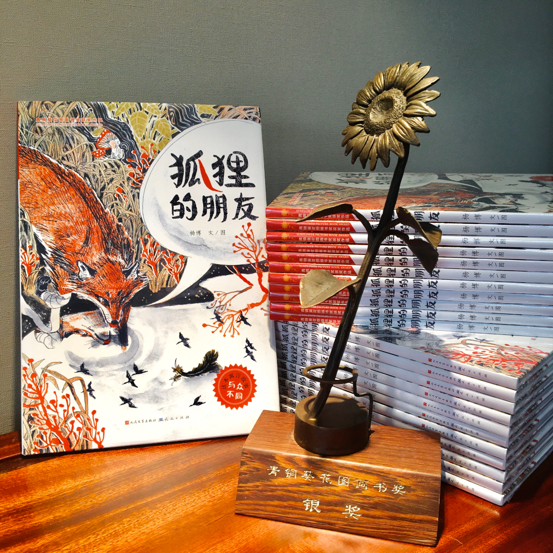 A pile of chinese picturebooks and a metal flower trophy