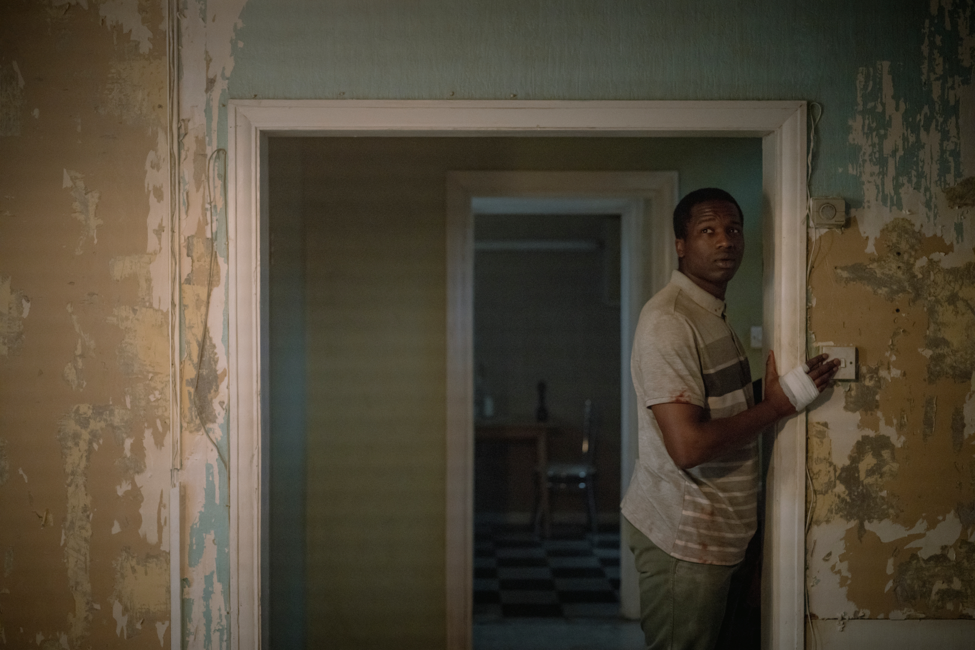 Still from 'His House' showing man in undecorated room