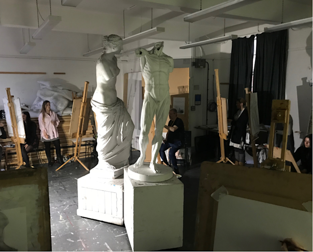 Female student at easel studying sculpted life models