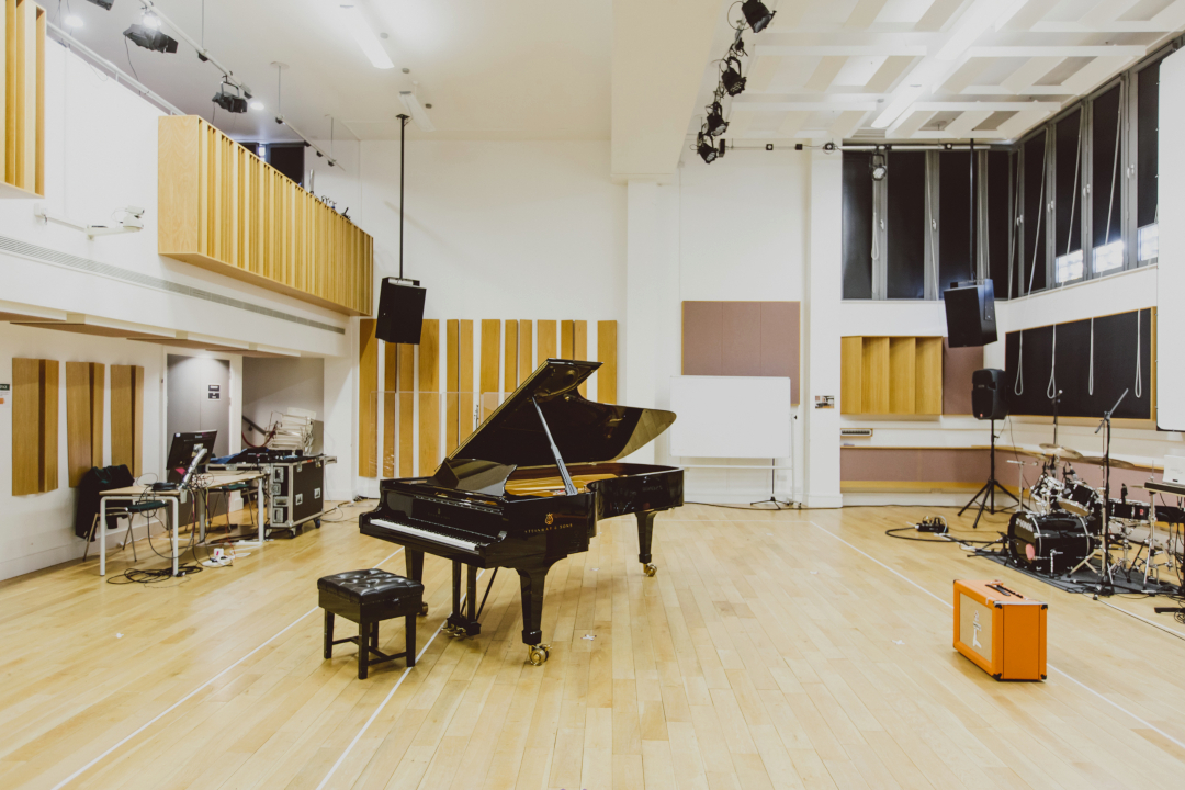 Baby grand piano and drum kit in recital hall