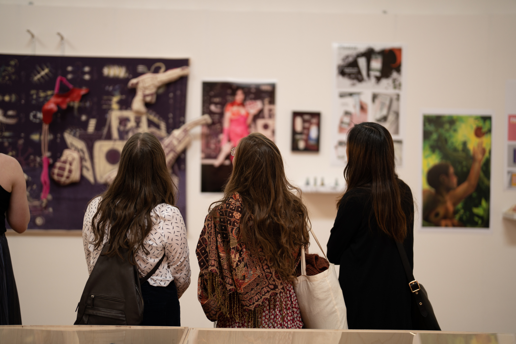 Three woman looking at various artwork on gallery wall