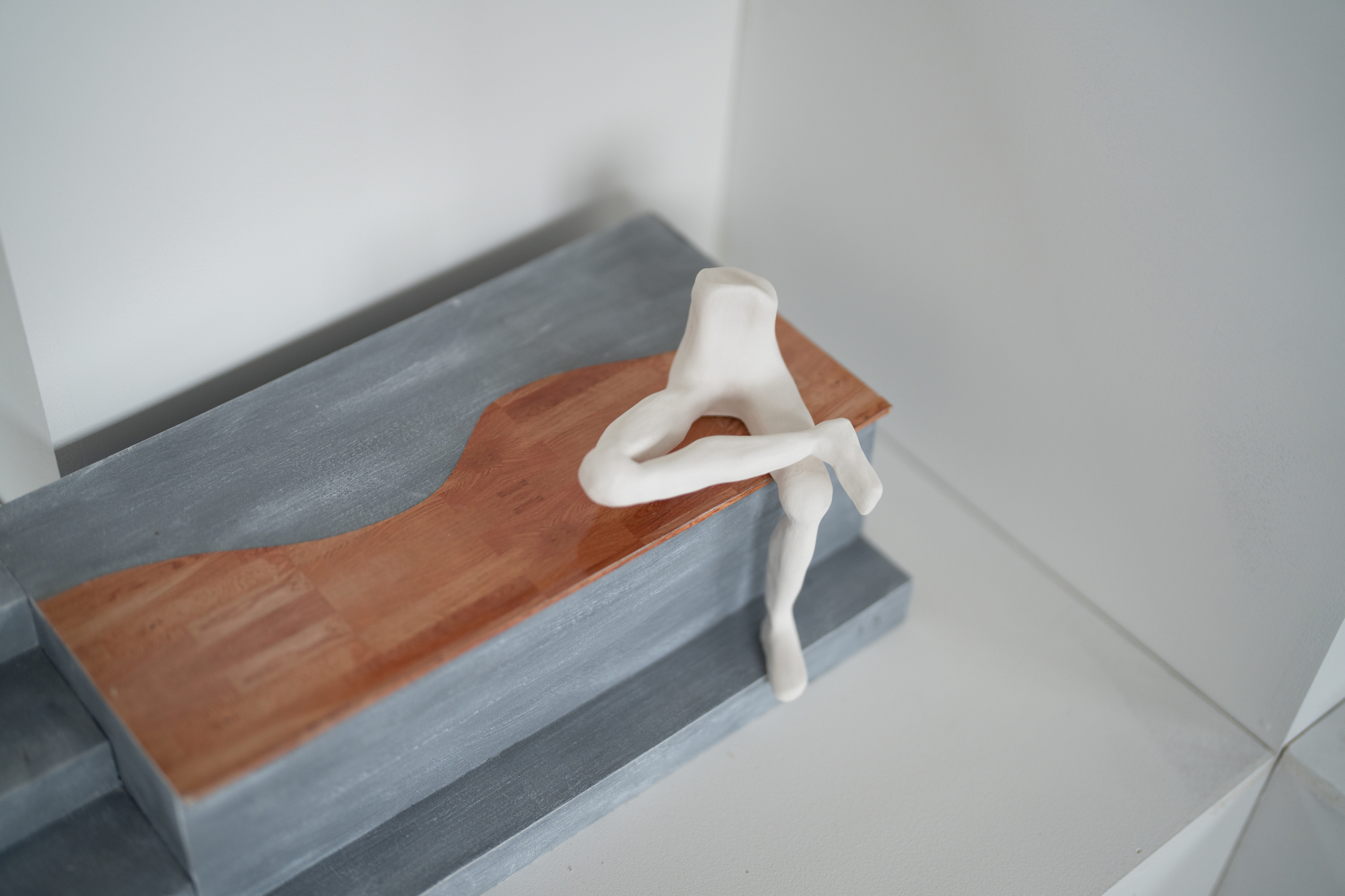Model of torso and legs sitting on large grey and brown bench