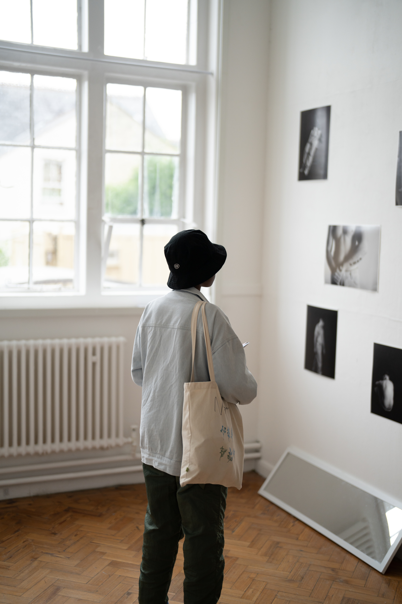 A person in hat looking at photographs on wall