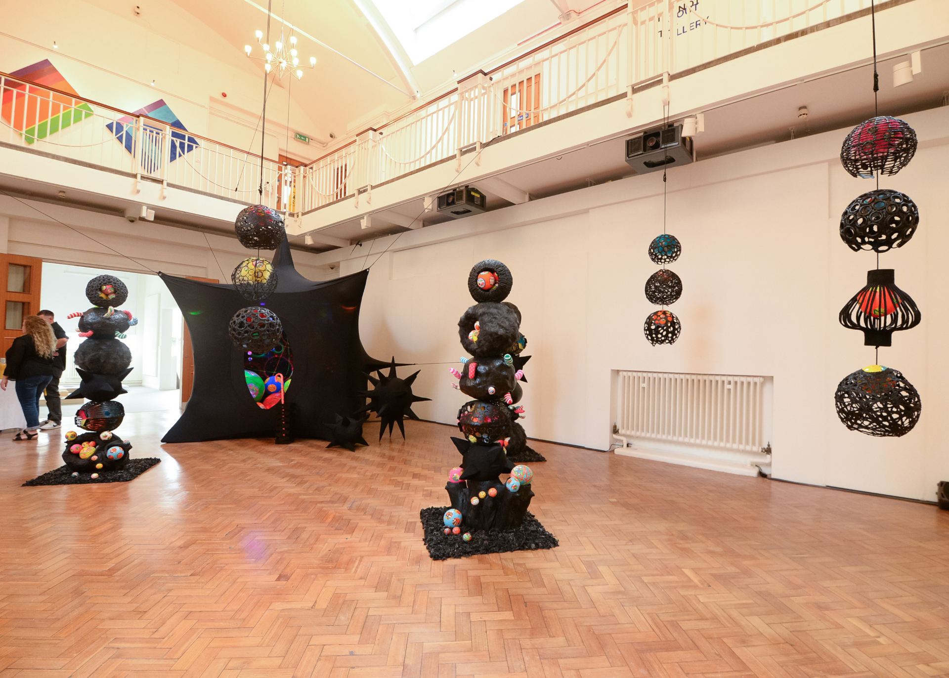 Black and spikey tent with ball-and-spike sculptures in gallery
