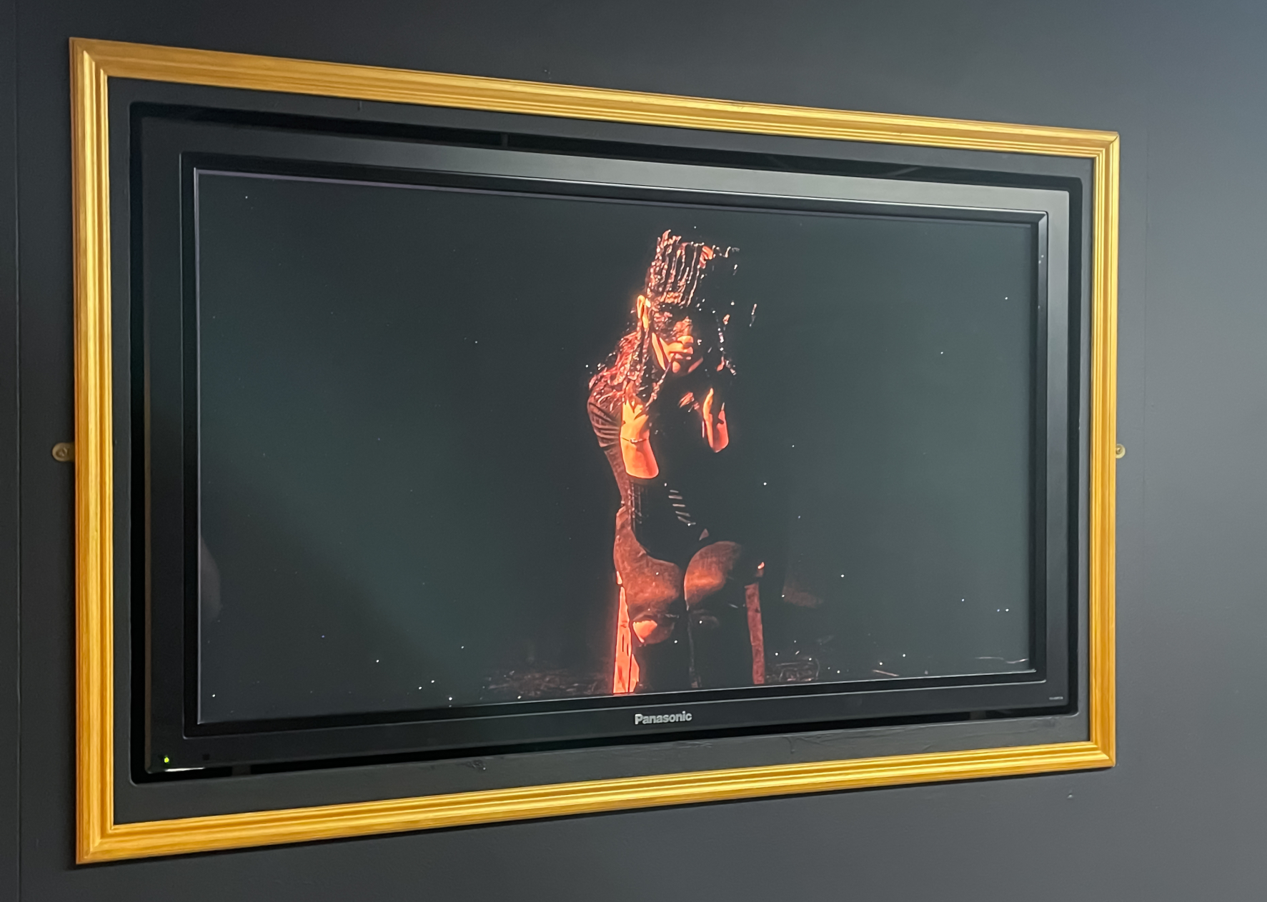 Gold-framed video screen displaing female demon in gallery