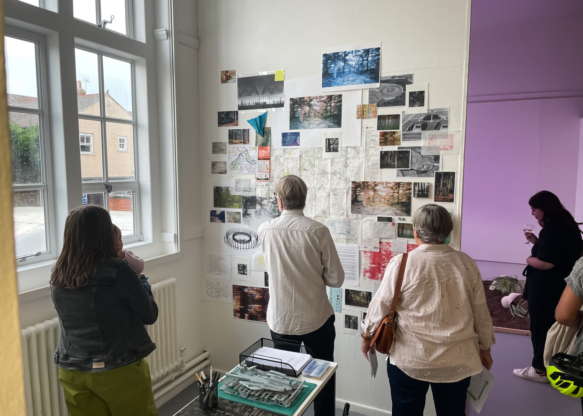 Visitors examining art exhibit on wall of studio