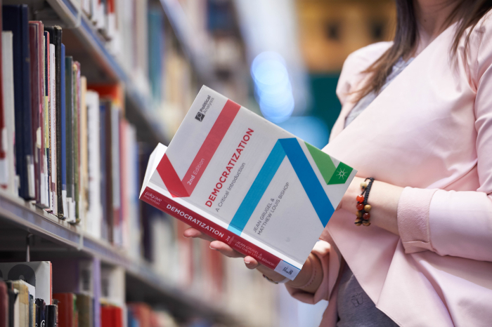 Female student holding politics textbook in library