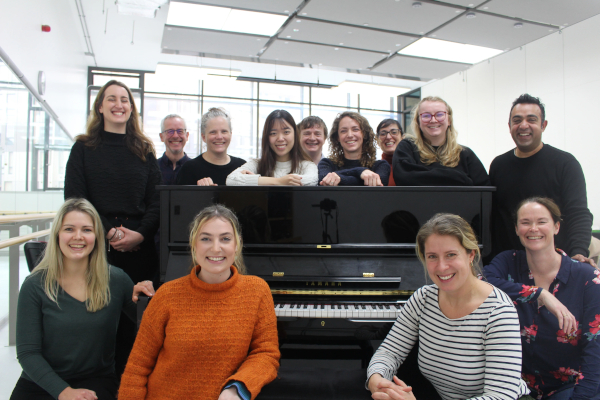 Music therapy team gathered round upright piano